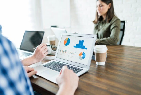 businessman-analyzing-graphs-laptop-while-working-with-colleague-office